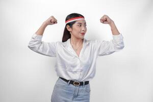 jovem ásia mulher cheio do confiança levantando uma punho acima mão placa gesto, vestindo bandeira arco de cabelo e branco camisa, exibindo uma Forte menina pose. independência dia conceito foto