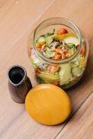 tremendo salada dentro jarra ou pedreiro salada jarra com morango, pepino, tomate, cenoura e alface folha servido dentro prato isolado em mesa lado Visão do saudável orgânico salada foto