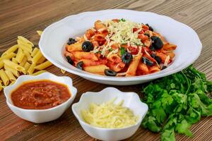 tomate molho massa com Pimenta molho, azeitonas e coentro servido dentro prato isolado em mesa lado Visão do árabe Comida foto