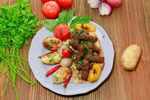 kofta Kebab rato carne kabab com tomate, cebola batata e coentro servido dentro prato isolado em mesa topo Visão do árabe Comida foto