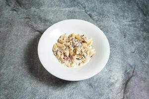 Macarrão Penne carbonara com branco creme queijo molho servido dentro prato isolado em fundo topo Visão do velozes Comida italiano primo foto