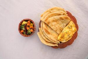 desi café da manhã misturado vegetais, ovo omelete e paratha servido dentro prato isolado em fundo topo Visão do Bangladesh café da manhã foto