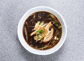 tailandês arroz macarrão dentro sopa com trincado frango servido dentro prato isolado em cinzento fundo topo Visão do hong kong Comida foto