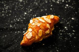 amêndoa croissant cobertura com nozes isolado em Sombrio fundo topo Visão do francês café da manhã cozido Comida item foto