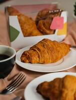avião croissant servido em de madeira borda com copo do Preto café isolado em guardanapo com faca e garfo lado Visão do francês café da manhã cozido Comida item em cinzento fundo foto