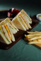 sortido clube sanduíche isolado em de madeira com maionese mergulho e francês fritas balde borda lado Visão do italiano velozes Comida em fundo foto