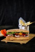 ciabatta defumado presunto sanduíche isolado em de madeira com maionese mergulho e francês fritas balde borda lado Visão do italiano velozes Comida em cinzento fundo foto