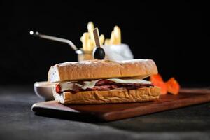 assado carne sub sanduíche com francês fritas balde servido em de madeira borda isolado em Sombrio fundo lado Visão do café da manhã Comida foto