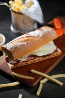 assado carne sub sanduíche com francês fritas balde servido em de madeira borda isolado em Sombrio fundo lado Visão do café da manhã Comida foto