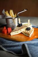 grelhado frango sanduíche com fritas balde servido dentro de madeira borda isolado em guardanapo lado Visão do café da manhã Comida foto