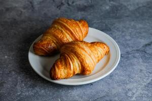 avião croissant servido dentro prato isolado em cinzento fundo lado Visão do francês café da manhã cozido Comida item foto