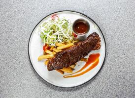 americano carne asa com francês fritas, molho, tomate e repolho salada servido dentro prato isolado em fundo topo Visão do hong kong Comida foto