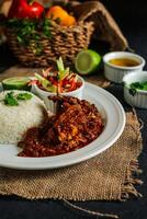 jamaicano Carneiro molho com avião arroz, salada, tomate, pepino mergulhar, molho e Sino Pimenta servido dentro prato isolado em guardanapo lado Visão do almoço Comida foto