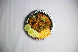 picante frango chaap com tomate e pepino servido dentro prato isolado em fundo topo Visão do Bangladesh, indiano e paquistanês tradicional picante Comida foto