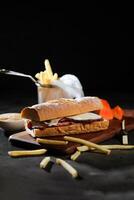 assado carne sub sanduíche com francês fritas balde servido em de madeira borda isolado em Sombrio fundo lado Visão do café da manhã Comida foto