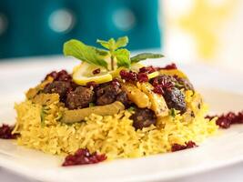 Kalam polow com arroz cobertura com carne, Lima vista e romã sementes servido dentro prato isolado em mesa fechar-se topo competir do árabe picante Comida foto