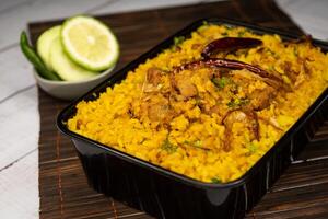 achari frango khicuri Biryani arroz pulao com pepino e limão fatia servido dentro prato isolado em de madeira mesa lado Visão fechar-se do Bangladeshi e indiano picante almoço Comida foto