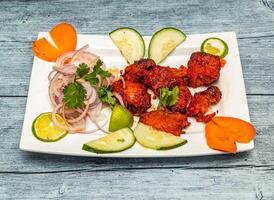 açafrão peixe tikka com limão e cebola servido dentro prato isolado em de madeira mesa topo Visão do indiano picante Comida foto