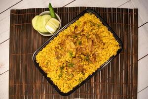 frango khicuri Biryani arroz pulao com pepino e limão fatia servido dentro prato isolado em de madeira mesa topo Visão do Bangladeshi e indiano picante Comida foto