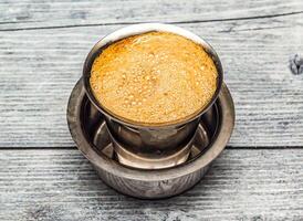 filtro café servido dentro aço copo isolado em de madeira mesa topo Visão do indiano quente beber foto