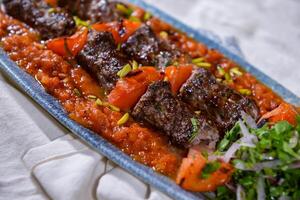 kesh dinheiro seeh kabab carne Kebab com tomate amassado molho e cebola servido dentro prato isolado em Comida mesa topo Visão do meio leste especiarias foto