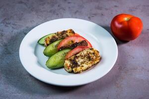 grelhado halloumi com tomate e pepino servido dentro prato isolado em cinzento fundo topo Visão do bahrain Comida foto