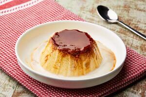 creme caramelo pudim com colher e guardanapo servido dentro prato isolado em mesa topo Visão do árabe Comida foto