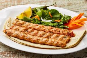 churrasco frango seeh kabab com limão fatia e salada servido dentro prato isolado em mesa topo Visão do árabe Comida foto