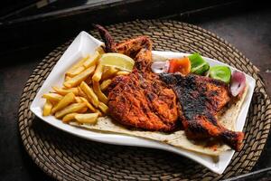 cheio frango grade com fritas e salada servido dentro prato isolado em vermelho esteira topo Visão em mesa árabe Comida foto