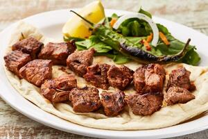 carne tikka boti cababa com Lima fatia e salada servido dentro prato isolado em mesa topo Visão do árabe Comida foto