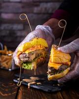 recheado hamburguer segurando dentro mão com derretido queijo, frango, alface folhas e ovo servido dentro prato isolado em de madeira mesa lado Visão do árabe Comida foto