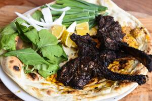 Cordeiro Picar ou Carneiro costeletas com bahraini pão tandoori nan, Lima e salada servido dentro prato isolado em de madeira mesa topo Visão meio Oriental grelha Comida foto