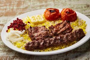 carne sultão com Andana kabab, carne tikka e mandi Biryani arroz, tomate e cebola servido dentro prato isolado em mesa topo Visão do árabe Comida foto