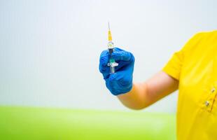 médico ou enfermeira mão dentro azul luvas segurando seringa com vacina para uma bebê ou adulto. remédio e droga conceito. foto