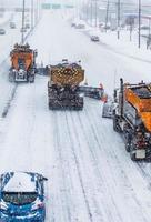 limpadores de neve alinhados com árvores limpando a rodovia foto