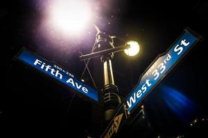 poste de luz e placa de rua da quinta avenida na esquina da rua oeste 33 em manhattan, nova york. foto