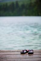 chinelos em uma doca em frente a um lago de água azul-turquesa foto