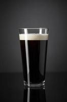 chope de nitrogênio fresco e cremoso cerveja preta forte sobre fundo preto foto