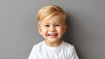 sorridente criança pequena Garoto dentro branco camisa contra cinzento fundo foto