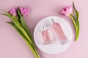 dois transparente garrafas do diferente formas com perfume mentira em uma volta branco pódio entre tulipas. beleza e perfumaria conceito. topo visualizar. foto