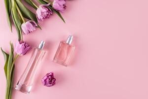 dois à moda vidro garrafas com perfume em uma Rosa fundo entre Primavera flores uma cópia de espaço. topo visualizar. perfume e beleza conceito. foto