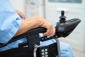 ásia Senior mulher paciente em elétrico cadeira de rodas com controlo remoto ao controle às hospital, saudável Forte médico conceito. foto