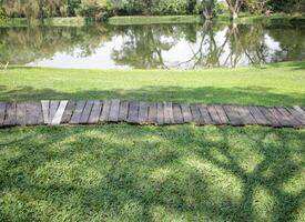 linha do de madeira passarelas dentro a jardim com uma lagoa dentro a fundo foto