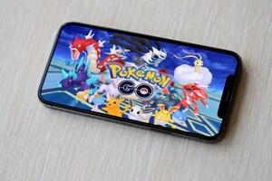 Pokémon ir Móvel ios jogos em Iphone 15 Smartphone tela em de madeira mesa durante Móvel jogabilidade foto