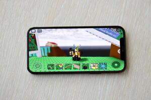 roblox Móvel ios jogos em Iphone 15 Smartphone tela em de madeira mesa durante Móvel jogabilidade foto