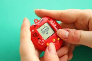 Kyiv, Ucrânia - marcha 9, 2024 retro animal chaveiro jogos tamagotchi dentro vermelho plástico caso dentro fêmea mãos foto