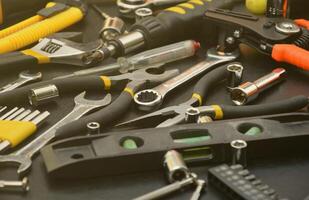 kit de ferramentas de faz-tudo na mesa de madeira preta. muitas chaves e chaves de fenda, empilhadeiras e outras ferramentas para qualquer tipo de reparo ou construção. ferramentas de reparador foto