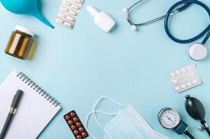 médico conceito, plano deitar em azul fundo. cópia de espaço dentro Centro. estetoscópio, tonometro, pílulas e de outros médico equipamento em azul, topo Visão foto