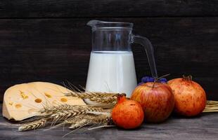 jarro com leite, queijo trigo e frutas shavuot conceito foto