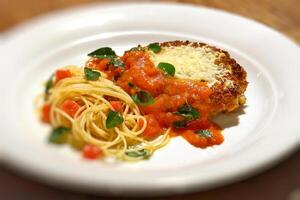 filé al parmigiano com espaguete com picado tomates foto